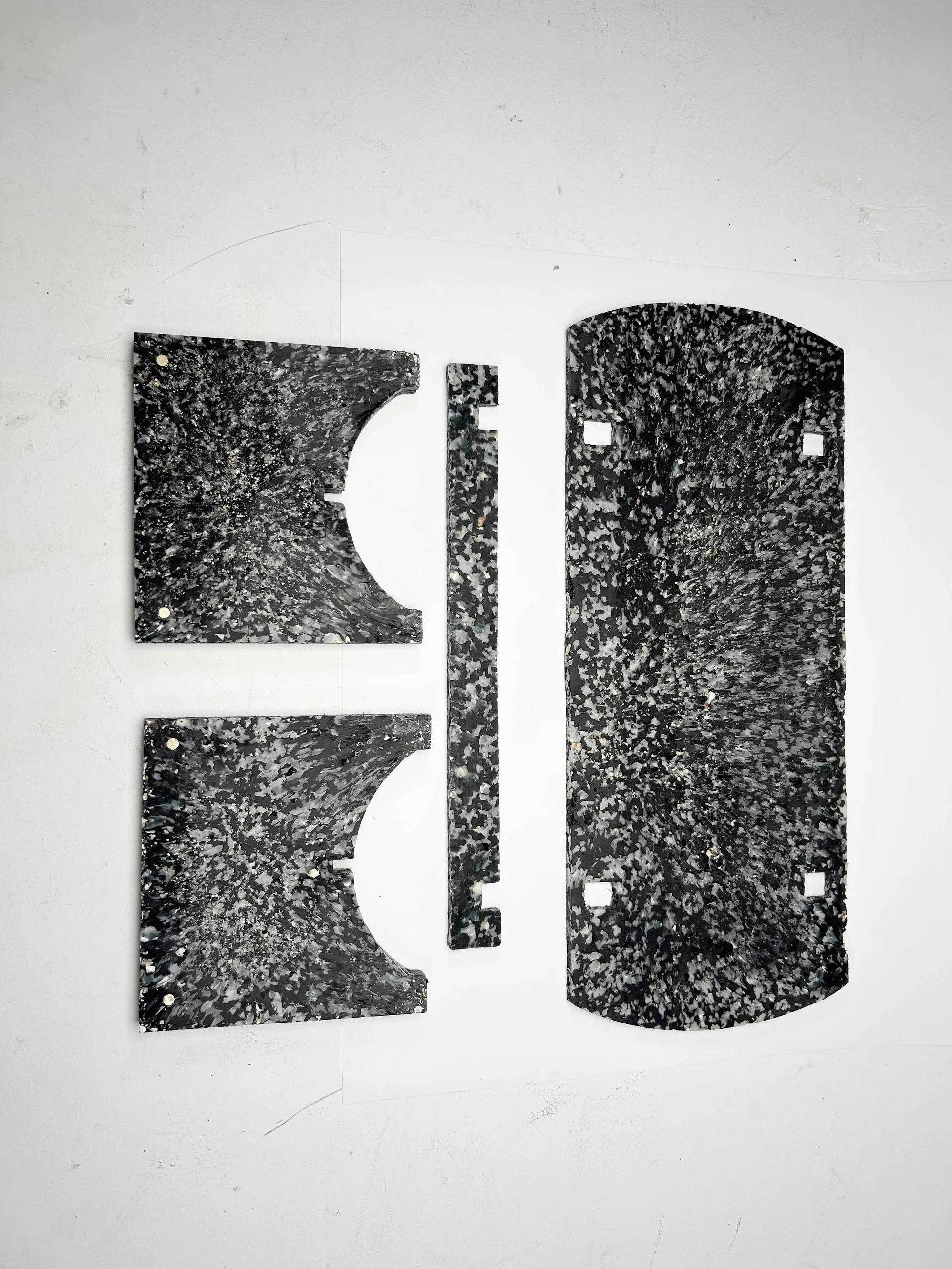 The four flat-pack components of the bench laid out, showing the terrazzo-like shell composite.